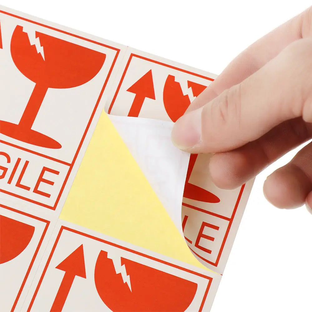 person peeling a fragile warning sticker off a sheet